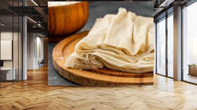 Homemade filo dough on a dark table lies on a wooden board. Wall mural