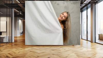 Portrait of a cheerful young woman with loose hair behind a curtain in the bathroom  Wall mural