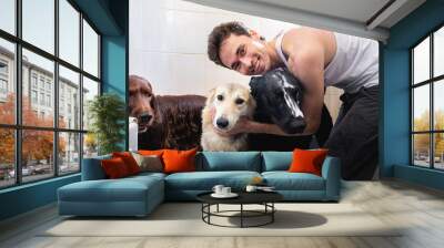 Smiling owner hugging obedient Shepherd and Irish Setter dogs while washing in bathtub Wall mural