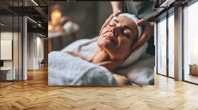 The cosmetologist's hands give an anti-aging facial massage to a beautiful woman. A spa treatment in a beauty salon.  Wall mural