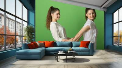 two beautiful positive girls with joyful emotions on a green background Wall mural