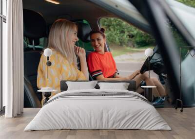 two teenagers, are sitting in the car. in yellow and red dresses,  outdoor Wall mural