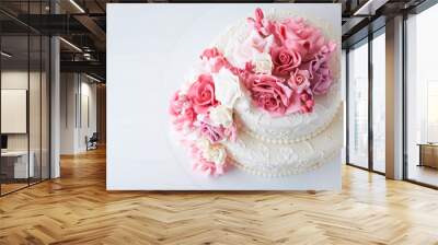 Two-tiered white wedding cake decorated with pink flowers on a white wooden background. Top view. Wall mural