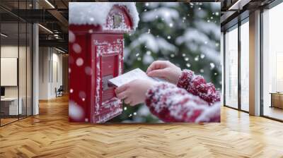 Child is putting an envelope in a red mailbox on a snowy christmas day Wall mural