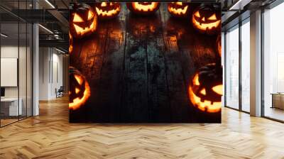 Halloween pumpkins with glowing eyes forming a circle on a dark wooden background, creating a spooky and festive atmosphere Wall mural