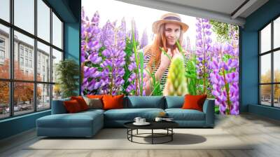 Beautiful young woman in hat  in lupine field Wall mural