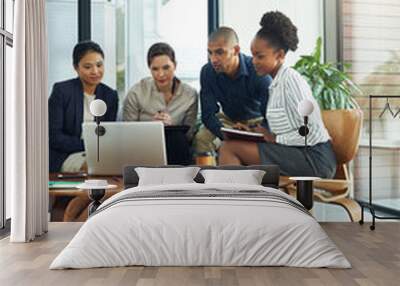 Everyones got their thinking cap on for this meeting. Shot of a group of businesspeople talking together over a laptop during a meeting. Wall mural