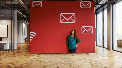 So many messages floating around in the atmosphere. Shot of a young woman surrounded by messaging graphics on a red background. Wall mural