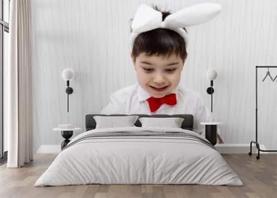 pre schooler boy with bunny rabbit ears headband and red bow at neck isolated pointing with finger up wow amazed shocked expression.child kid in baby crib or at table desk using laptop smiling easter Wall mural