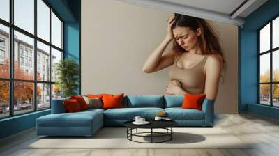 Pregnant woman feeling unwell, touching her belly and her head with a painful expression Wall mural