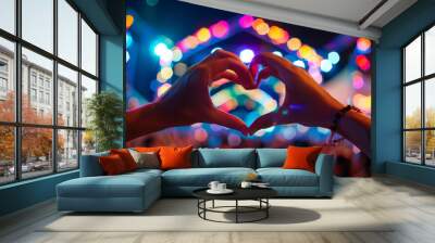 Silhouetted hands forming a heart shape against a vibrant concert backdrop with colorful stage lights and excited crowd atmosphere Wall mural