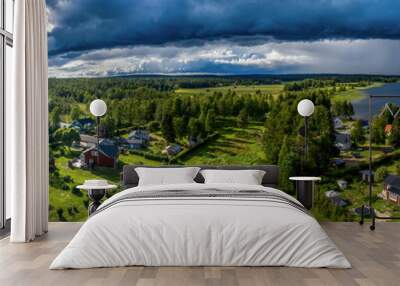 Aerial Panorama of Scandinavian pine tree forest landscape, summer village with Sunny and rainy areas, clear blue sky, white clouds, green yellow fields. View on typical landscape of Northern Sweden Wall mural