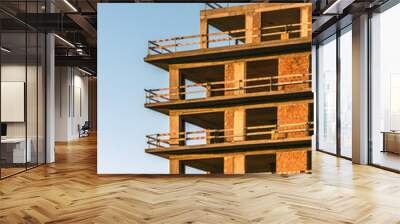 Construction of a modern building against a clear blue sky at sunset Wall mural