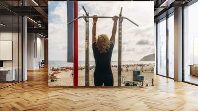 Mature woman (70-79) doing pull up exercises at public gym overlooking Ipanema Beach, Rio de Janeiro, Brazil Wall mural