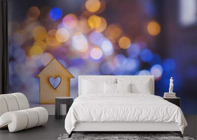 Wooden icon of house with hole in the form of heart with little heart on colorful bokeh background. Wall mural