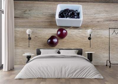 Cherry jam with two cherries on wood background Wall mural