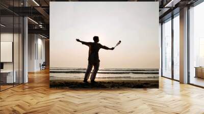 Senior woman practicing tai chi balloon ball on the beach at sunset Wall mural