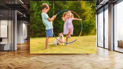 Children playing with pet dog jumping through hula hoop Wall mural