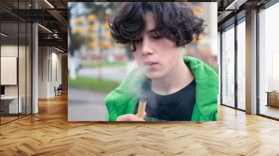 a young guy addicted to nicotine smokes an electronic cigarette. the dependence on cigarettes Wall mural