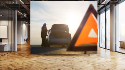 Emergency triangle sign set road near broken car with islamic woman. Wall mural