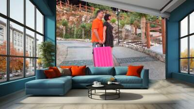 Family couple of tourists with big suitcase rent apartment. Wall mural