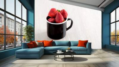 Fresh ripe strawberries in black metal cup on wooden background Wall mural