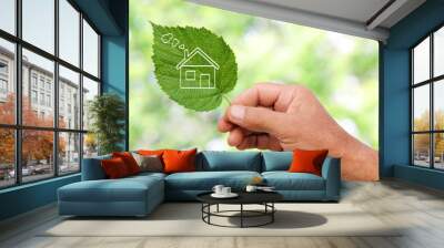 Eco house concept, hand holding eco house icon in nature Wall mural