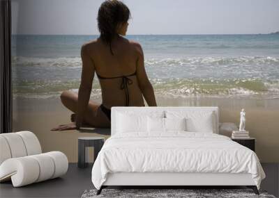 Young girl sitting on the sand with shell   Wall mural