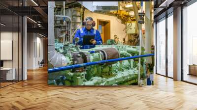 Marine Engineer in blue overall working in Engine room of ship. Work at sea. Motorman. Wall mural