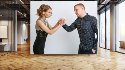 The girl wrapped her arms around the hand of the guy who clenched his fist Wall mural