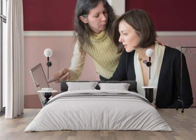 two young smartly dressed women filling out forms at a vintage office desk in front of a laptop Wall mural