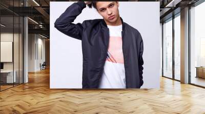 Young man in jeans, black bomber jacket on white background. Wall mural