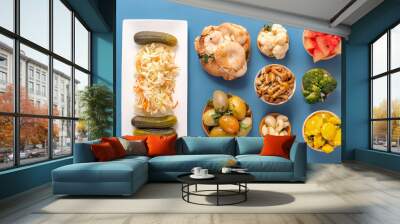 Fermented products cabbage, peppers, pickles, tomatoes, mushrooms, zucchini, garlic on a blue table. Top view Wall mural