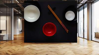 White, black and red empty plates with chopsticks in an oriental style lie on a dark table in a minimalist composition. Top view Wall mural