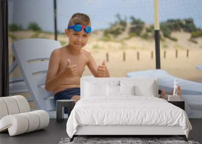 Young guy in swimming glasses is sunbathing on a sunbed on the sea beach. Wall mural