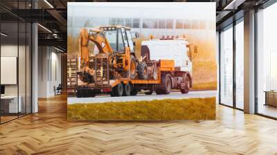 Flatbed Truck delivering heavy machinery to the construction site. Excavator tractor or crane. Construction industry. Wall mural