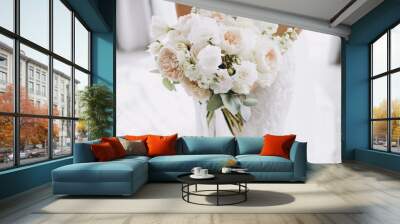 young girl in a white wedding dress holds in her hands a bouquet of flowers and greenery with a ribbon Wall mural