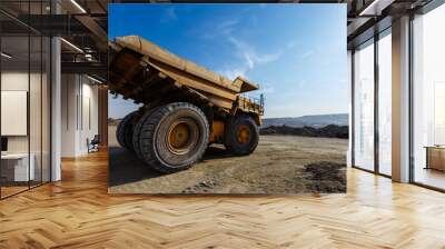 Industrial work in an open pit coal mine. A large yellow dump truck is carrying coal soil through the quarry. Open pit coal mining. Wall mural