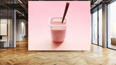 Strawberry yogurt or pudding  in white plastic cup on pink background with copy space. Raspberry pink yoghurt with spoon in it. Minimal style. Wall mural