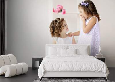 Cute little girls in white dresses talking. Wall mural