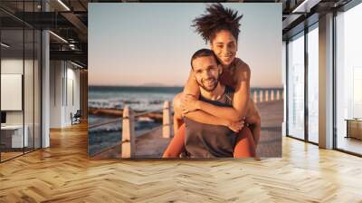 Fitness, beach and portrait of couple piggyback enjoy holiday, vacation and quality time on weekend. Love, summer and black man and woman relax after running, exercise workout and training by ocean Wall mural