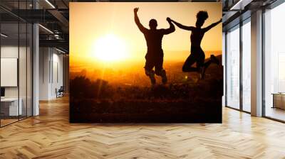 Sunset silhouette, couple jumping and a nature hike adventure for winning fitness exercise, fun holiday and city view. Summer cardio, outdoor training and workout motivation for body health success Wall mural