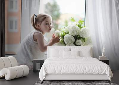 A little girl is sitting on the windowsill. A bouquet of flowers Wall mural