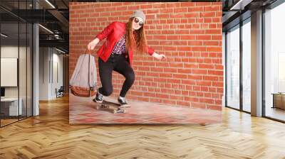 A young hipster girl is riding a skateboard. Girls girlfriends f Wall mural