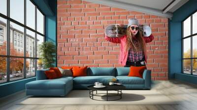 A young hipster girl is riding a skateboard. Girls girlfriends f Wall mural