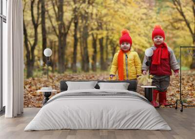 Children are walking in nature. Twilight kids are walking around the park. Brother with sister in autumn city park in leaf fall. Wall mural