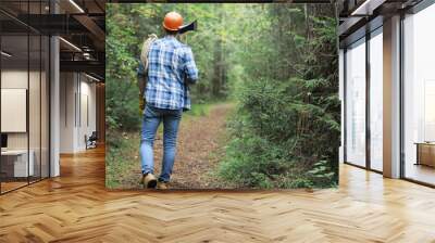 Male lumberjack in the forest. A professional woodcutter inspects trees for felling. Wall mural