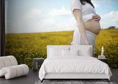 Pregnant woman in a dress in a field of flowers Wall mural