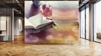 Reading religious literature. A man studies the Koran and sorts out the rosary. Wall mural