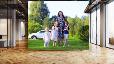 Young large family on a summer morning walk. Beautiful mother with children is playing in the park. Wall mural